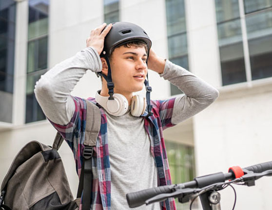 Chico estudiante poniendo el casco para circular en patinete eléctrico